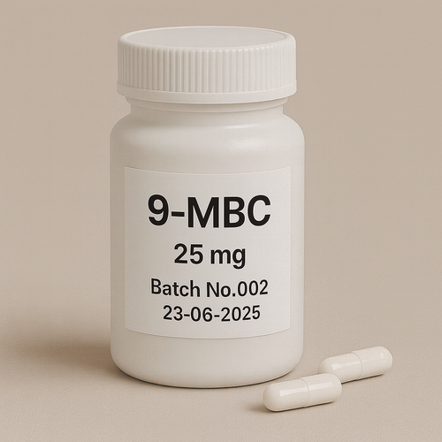 White plastic pill bottle labeled "9-MBC, 25 mg, Batch No.002, 23-06-2025" on a beige background, with two white capsules lying beside it.