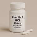 White plastic pill bottle labeled "Phenibut HCL, 200 mg, Batch No.002, 18-06-2025" on a beige background, with two white capsules lying beside it.